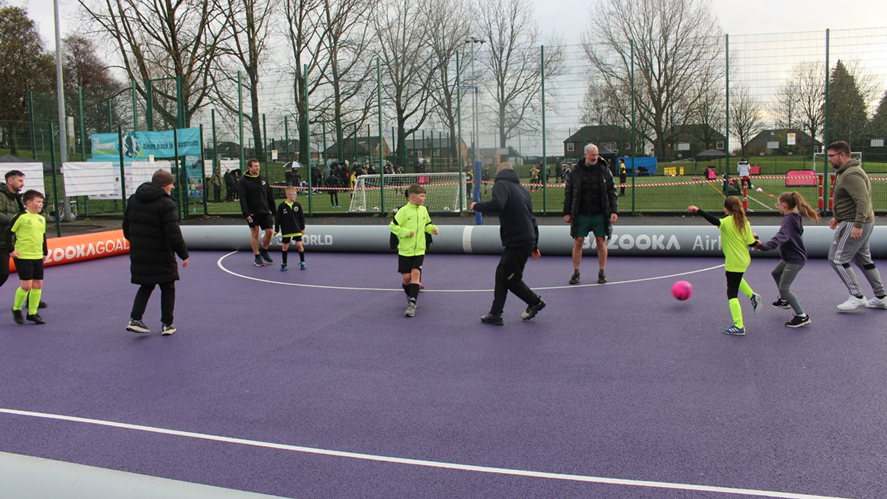 Young players and coaches running a small-sided game on the purple futsal court during the Grassroots Coachathon.