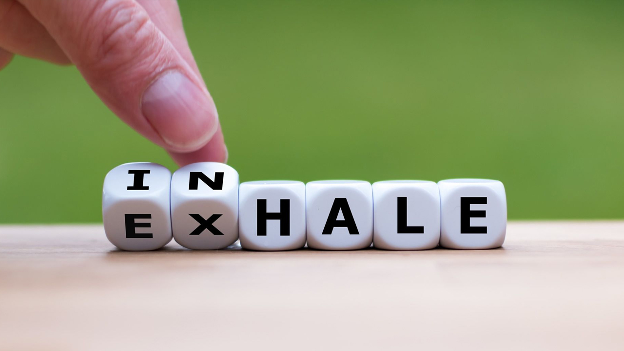 Hand flipping dice to change the word from 'exhale' to 'inhale'